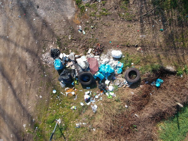 basura y neumáticos abandonados en el campo cerca de la carretera. Vista aérea, plana
 - Foto, Imagen