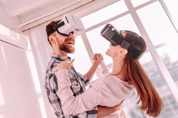 Cheerful boyfriend and girlfriend moving in VR glasses - Фото, изображение