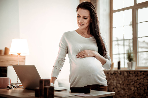 Positive delighted pregnant woman enjoying her work - Фото, изображение