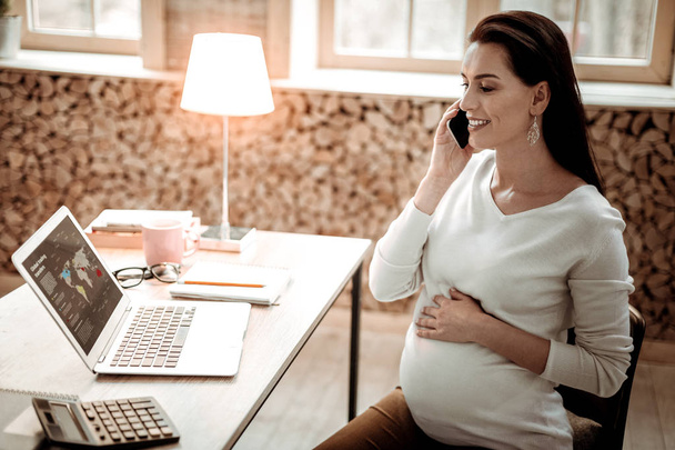 Delighted professional pregnant businesswoman answering the call - Foto, Imagem