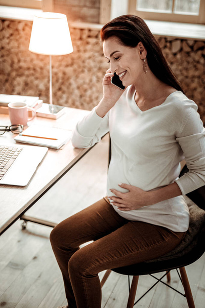 Happy pregnant woman having a phone conversation - Photo, image