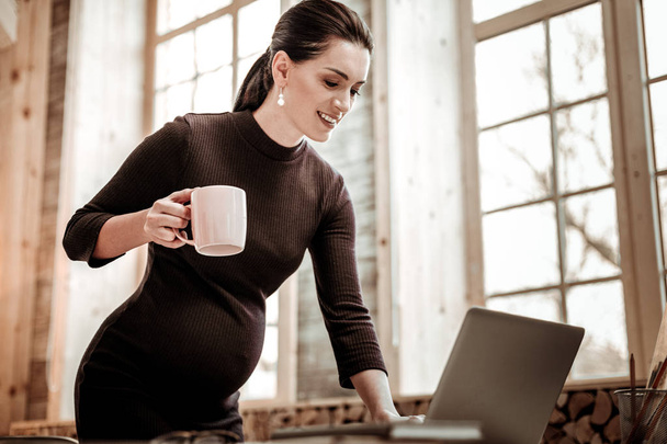 Nice pregnant woman leaning over the laptop - Fotó, kép