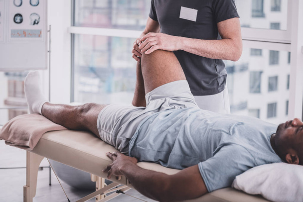 Расслабленный темнокожий мужчина посещает реабилитационный массаж
 - Фото, изображение