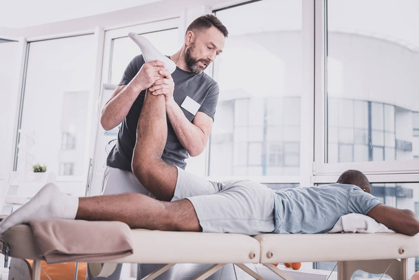Strong bearded man doing rehabilitation procedure for muscles - Photo, Image