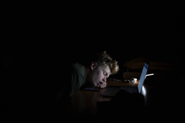 El hombre duerme cerca de un portátil por la noche
 - Foto, imagen