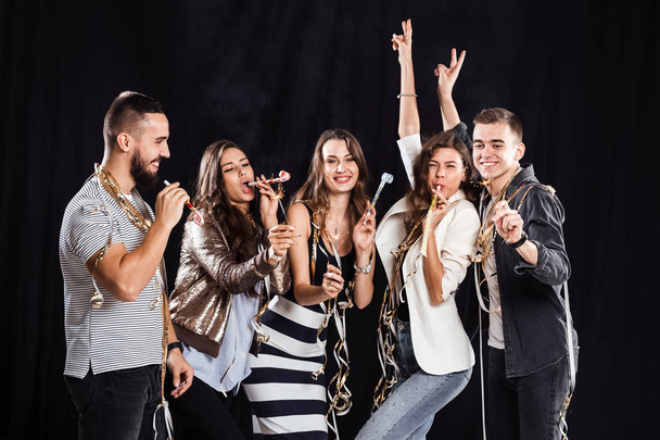 Party time. Company of friends in fashionable casual clothes rejoice and have fun on a black  background in the studio - Foto, Imagen