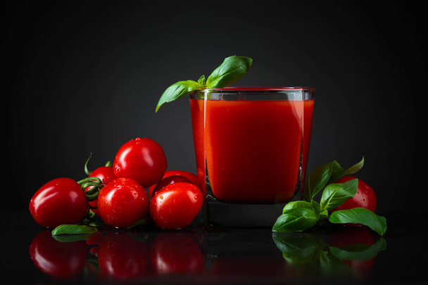 Jugo de tomate con tomates cereza y albahaca sobre mesa negra. Copia espacio para tu texto
. - Foto, imagen