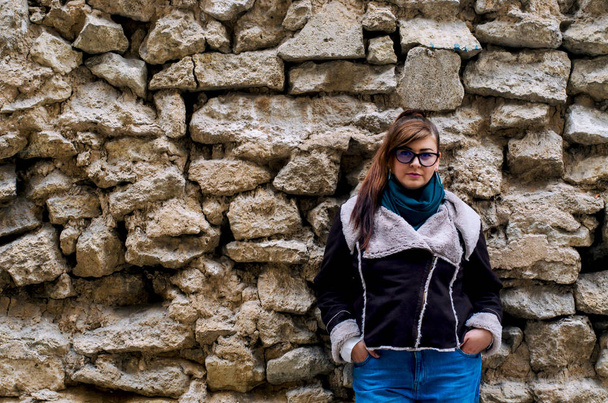 Model plus size in a stylish street look near the wall with raw stone. - Photo, Image