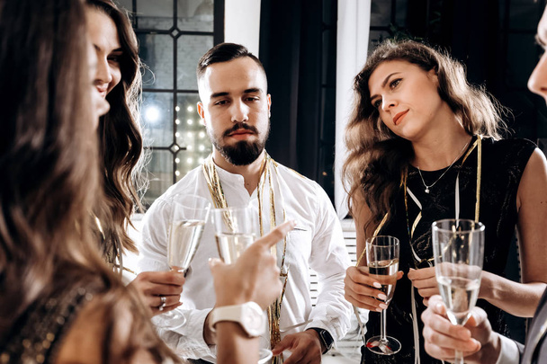 Company of friends dressed in stylish elegant clothes stand together and clink glasses with champagne. Party time - Foto, imagen