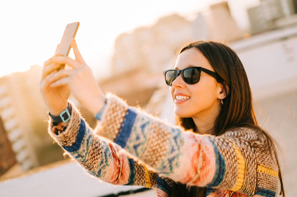 Happy young woman with sunglasses taking selfie on a terrace in New York - Fotó, kép
