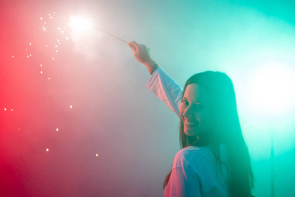 Vrij lachende jonge vrouw met grote en kleurrijke sparkler - Foto, afbeelding