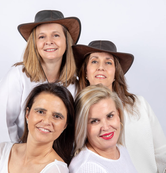 Groep 4 vrouwen, vrienden, middelbare leeftijd plezier in een fotosessie in een studio met witte achtergrond, zittend op een bal - Foto, afbeelding