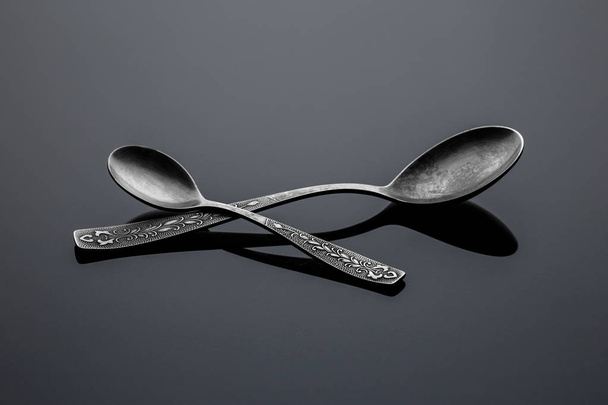 Old nickel silver spoons on a reflective surface - Fotoğraf, Görsel