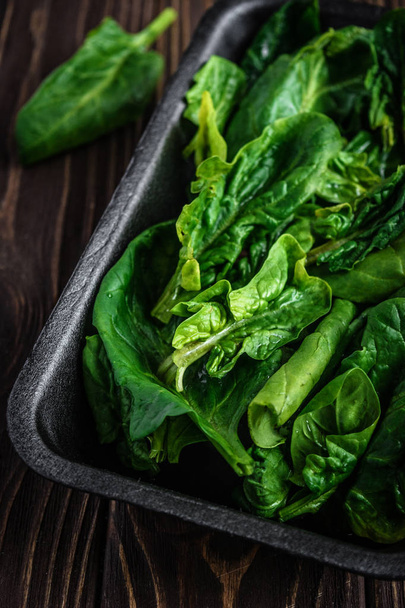 Yeşil ıspanak yaprakları. Ahşap bir masa üzerinde taze organik ıspanak. Vegan gıda, sağlıklı gıda. Karanlık rustik tarzı fotoğraf. - Fotoğraf, Görsel