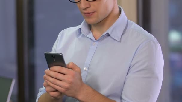 Male office worker scrolling smartphone, checking data in mobile business tool - Záběry, video