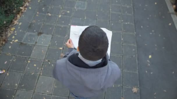 Male tourist with city map walking on street, looking for famous landmarks - Video