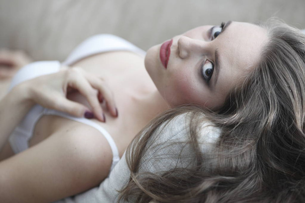Portrait of beautiful young woman in lingerie on sofa - Fotografie, Obrázek