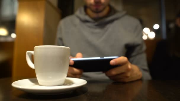 Young male scrolling smartphone in cafe, surfing internet, gadget addiction - Imágenes, Vídeo
