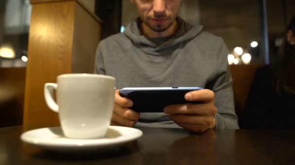 Hombre jugando videojuego en la cafetería, ganar mostrando sí gesto, adicción gadget
 - Imágenes, Vídeo
