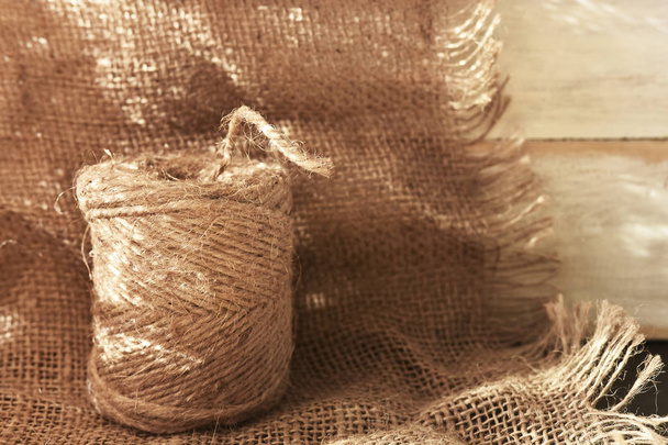 Un'immagine ravvicinata di una bobina di spago artigianale su uno sfondo di tessuto di iuta
.  - Foto, immagini