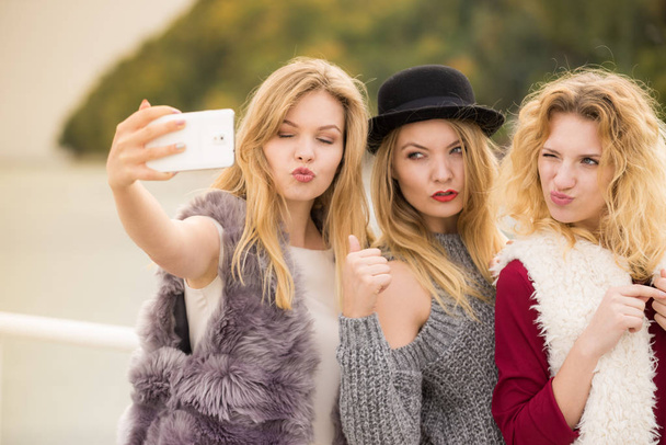 Three females taking selfies, having fun outdoor using smart phone to take photo. - Fotó, kép