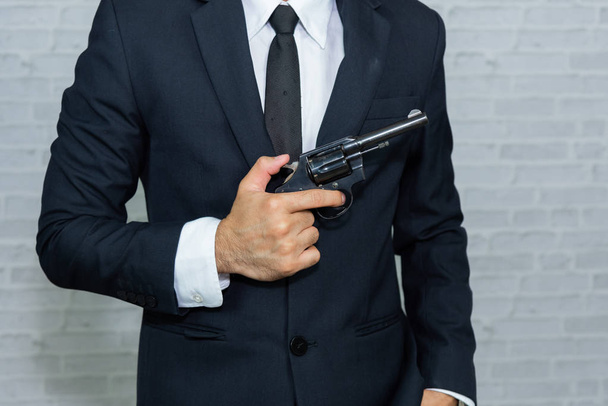 businessman with gun on gray background - Foto, afbeelding