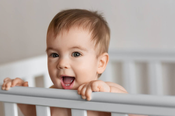 baby boy standing in crib - 写真・画像