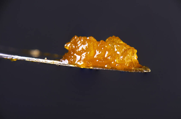 Macro detail of cannabis concentrate HTFSE extracted from medical marijuana isolated over black on a dabbing tool  - 写真・画像