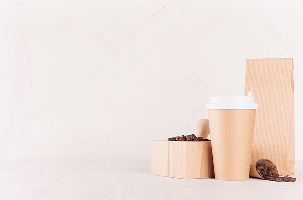 Шаблон кофейни для идентификации бренда - коричневая бумажная чашка, пакет, раствор с кофейными зёрнами на доске из белого дерева, место для копирования
. - Фото, изображение