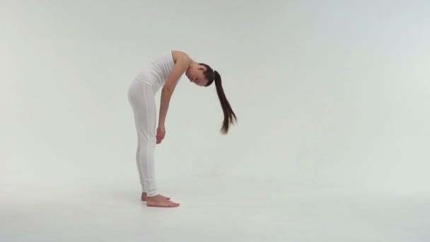 Молодая очаровательная спортивная женщина делает боковой мост на коврике для упражнений на белом фоне
. - Кадры, видео