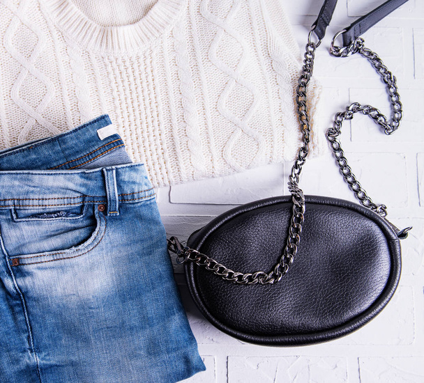 Black leather bag and womens clothing, jeans and sweater - Photo, Image