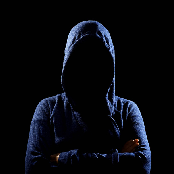 Silhouette einer bis zur Unkenntlichkeit verkleideten Frau in Kapuzenpulli auf Schwarz. Anonymes oder kriminelles Konzept - Foto, Bild