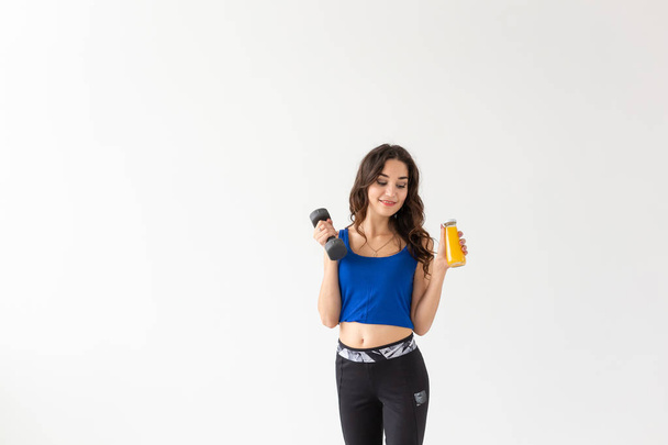 Sport, zdravý životní styl, lidé koncept - mladá žena s činka v ruce a láhev šťávy v jiné ruce, na bílém pozadí s kopií prostor - Fotografie, Obrázek