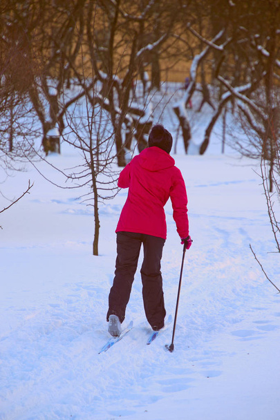 donna in giacca rossa sta sciando nel parco
 - Foto, immagini