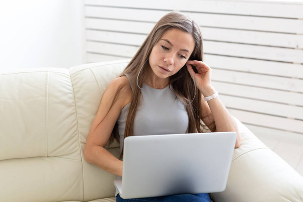 Freelance and people concept - Young woman sitting on a sofa and working at laptop - Foto, Bild