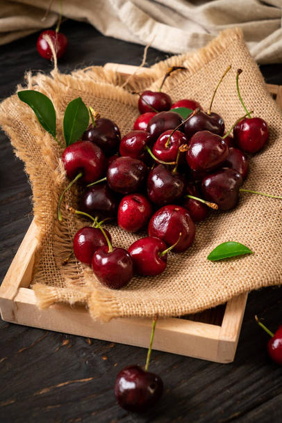 Fresh cherries in bowl  on wood background - Fotó, kép