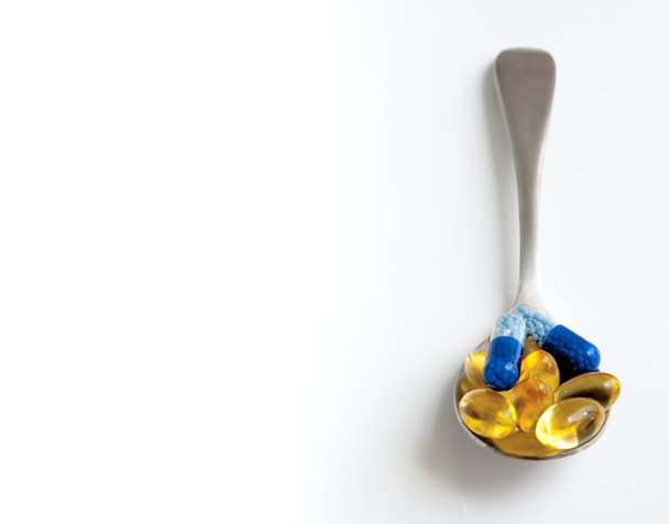 Gold and blue pills on a spoon - Photo, Image