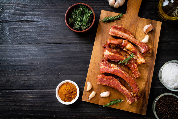 Fresh raw pork ribs ready for roasting with ingredients on wooden board - Фото, зображення