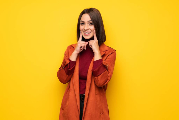 Young woman with coat smiling with a happy and pleasant expression - Photo, Image