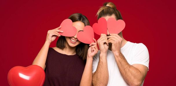 Couple dans la Saint-Valentin tenant un symbole de coeur sur fond rouge
 - Photo, image