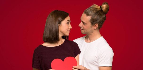Para w Walentynki gospodarstwa symbol serca na czerwonym tle - Zdjęcie, obraz