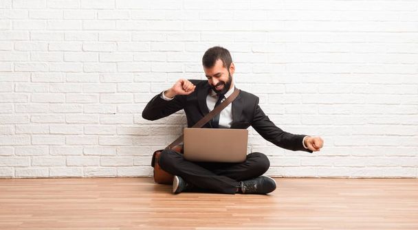 Un hombre de negocios con su portátil sentado en el suelo disfruta bailando mientras escucha música en una fiesta
 - Foto, imagen