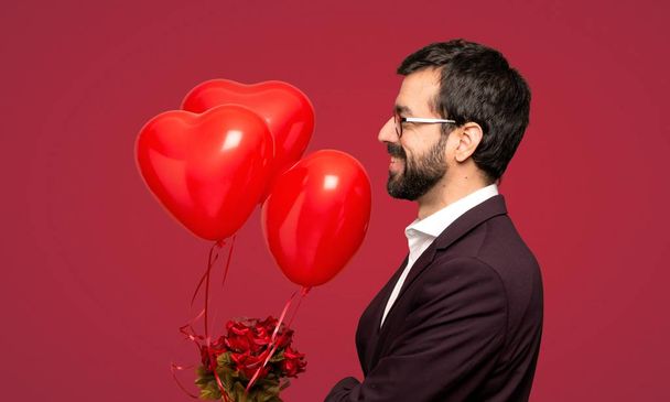 Mies ystävänpäivänä sivuasennossa punaisen taustan yläpuolella
 - Valokuva, kuva