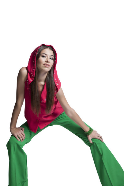 Hermosa chica en una blusa roja y pantalones verdes posando en el estudio
 - Foto, imagen