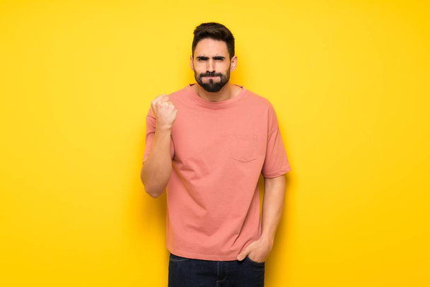 Handsome man over yellow wall with angry gesture - Photo, Image