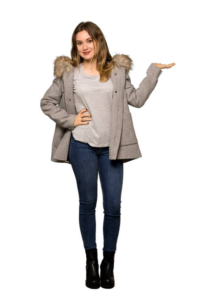 Un plan complet d'une adolescente avec un manteau tenant un copyspace imaginaire sur la paume pour insérer une annonce sur fond blanc isolé
 - Photo, image