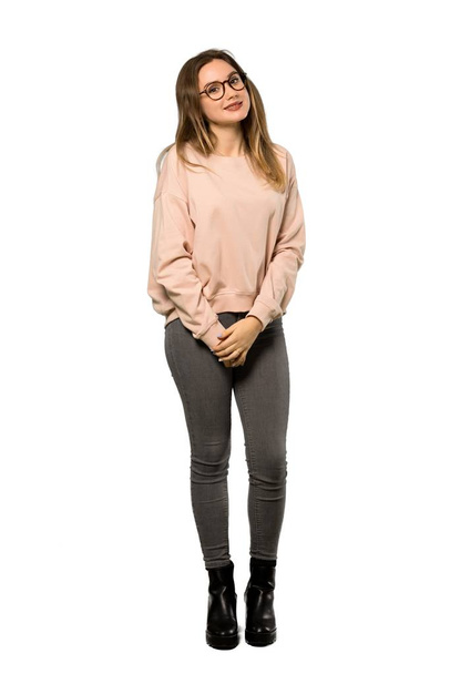 A full-length shot of a Teenager girl with pink sweater with glasses and happy over isolated white background - Foto, imagen