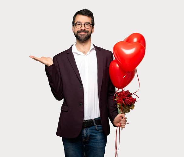 Mann am Valentinstag hält Kopierraum imaginär auf die Handfläche, um eine Anzeige über isoliertem grauem Hintergrund einzufügen - Foto, Bild