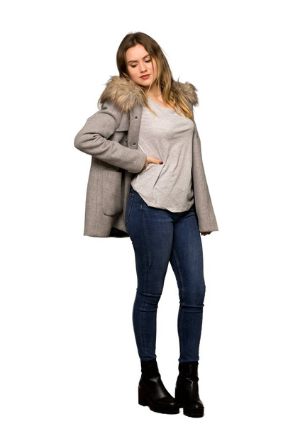 A full-length shot of a Teenager girl with coat suffering from backache for having made an effort on isolated white background - Foto, Imagen