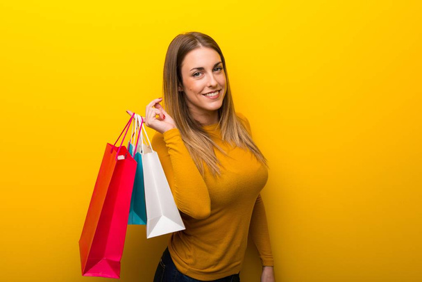 junge Frau auf gelbem Hintergrund mit vielen Einkaufstüten - Foto, Bild